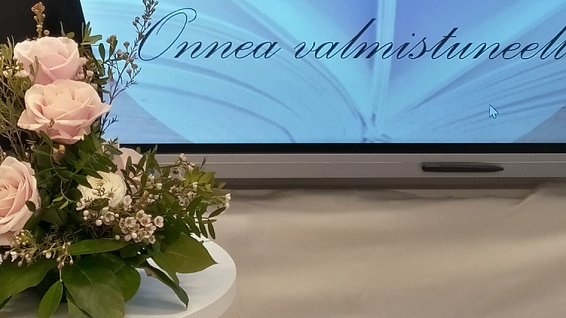 Vaalean punainen ruusuasetelma ja teksti Onnea valmistuneelle