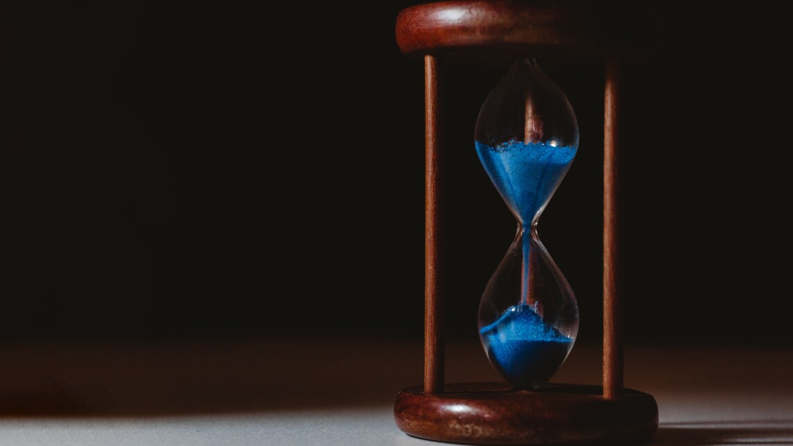 Tiimalasi, jossa sinistä hiekkaa sisällä.