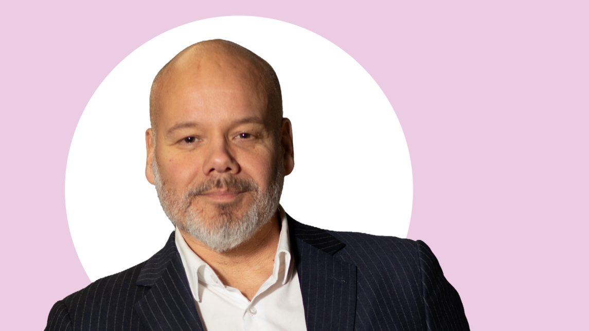 Heikki Jaatinen lähikuvassa, taustalla vaaleanpunaista ja valkoista.