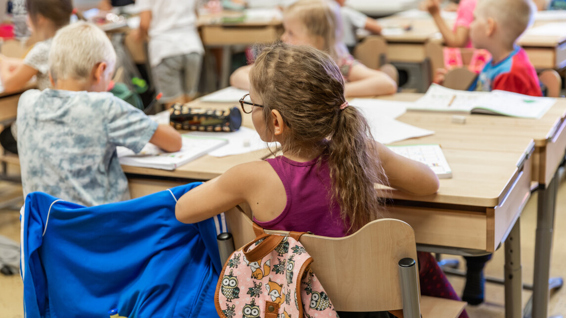 Koululaisia pulpettien ääressä istumassa.