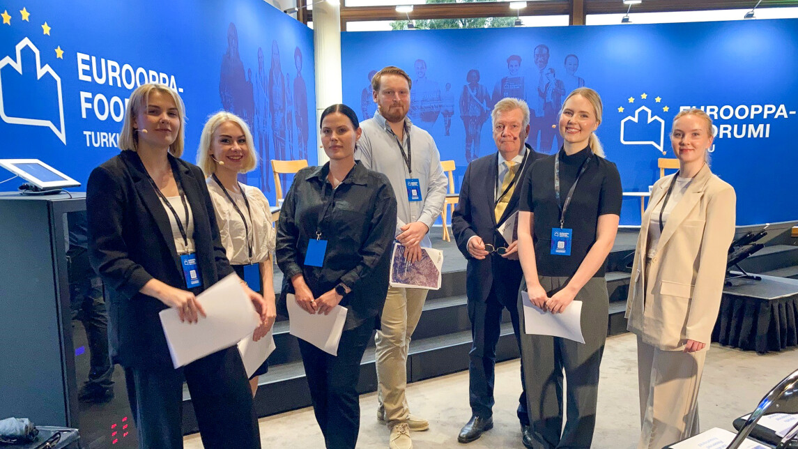 Joukko ihmisiä Eurooppa-foorumin seinän edustella.