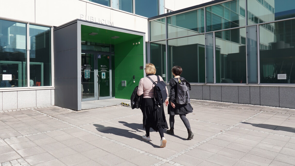 Kaksi naista kävelemässä sisälle rakennukseen.