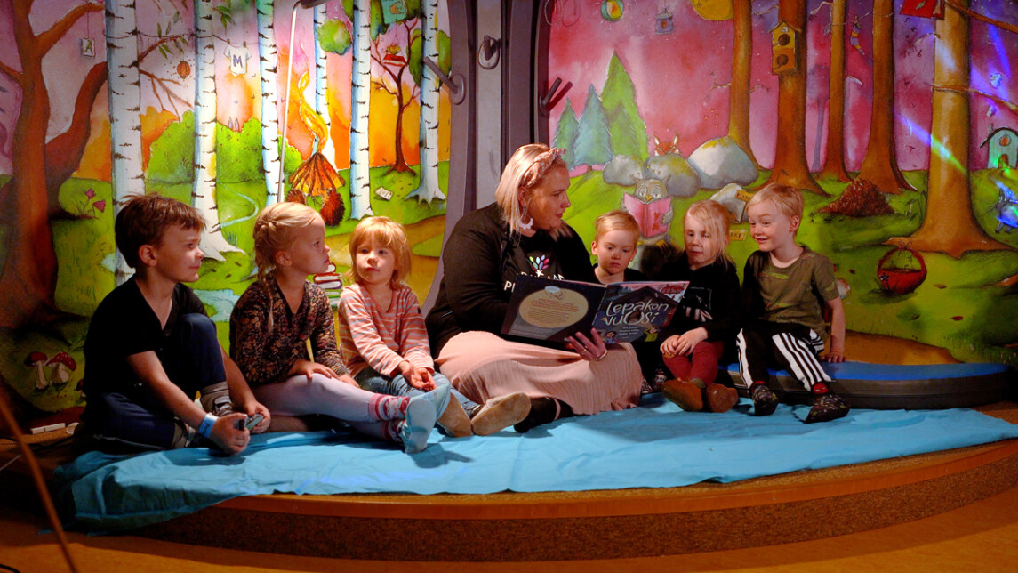 Aikuinen lukee kirjaa lapsille.