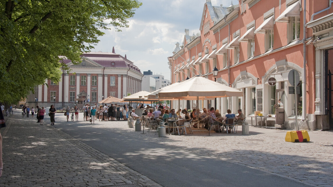 Turn vähätori kesällä. Taustalla kaksi historiallista rakennusta, joista toisen edessä ravintolan pöytiä suurten valkoisten aurinkovarjojen alla.