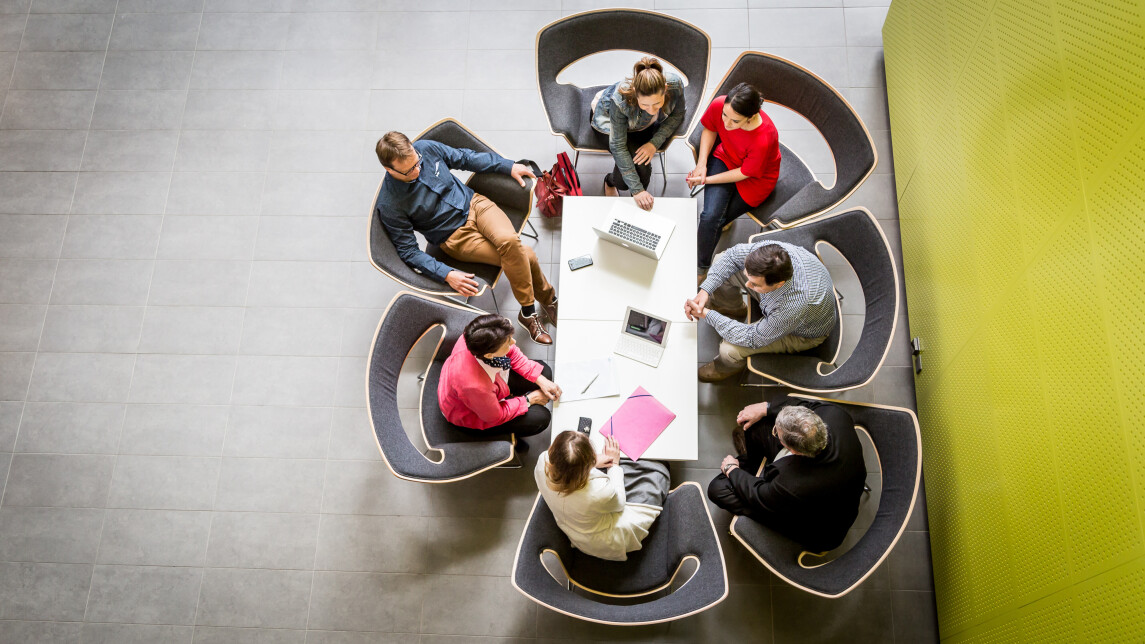 Ylhäältäpäin kuvattuja hmisiä istumassa saman pöydän äärellä