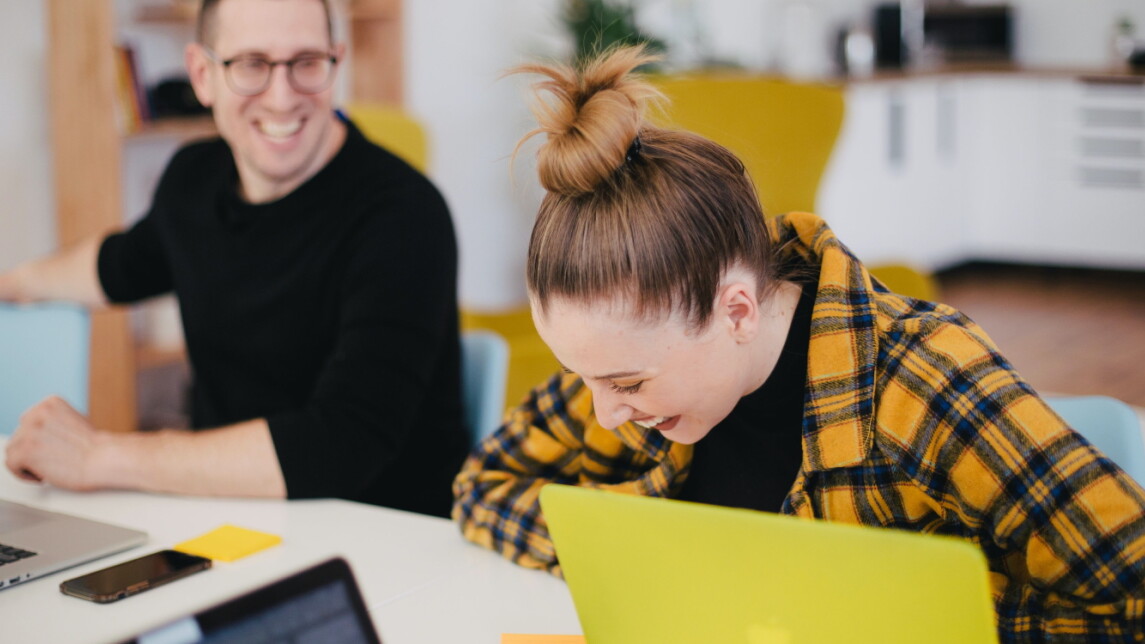 Mies ja nainen opiskelemassa pöydän ääressä kannettavat tietokoneet edessään.
