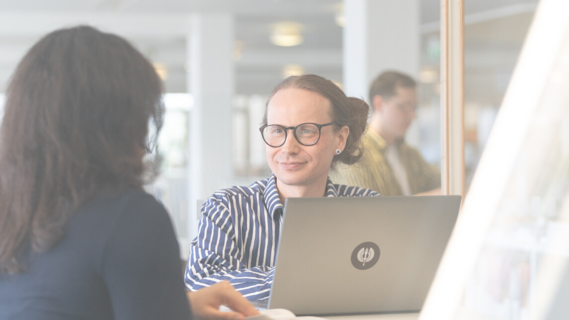 Kaksi henkilöä työskentelmässä yliopiston kirjastossa