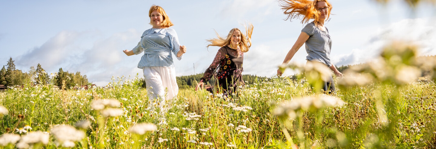 Päivi Onkamo, Virpi Lummaa and Outi Vesakoski jumping to the air in a field.