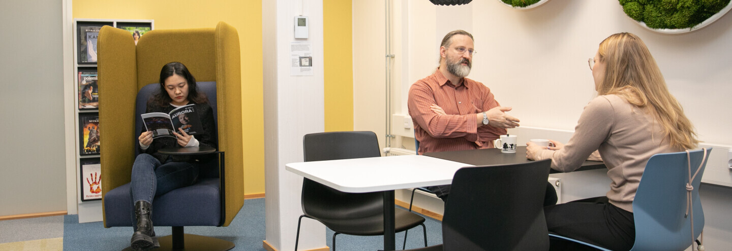 Ihmiset istuvat ja juttelevat kahvihuoneessa. Kuvituskuva