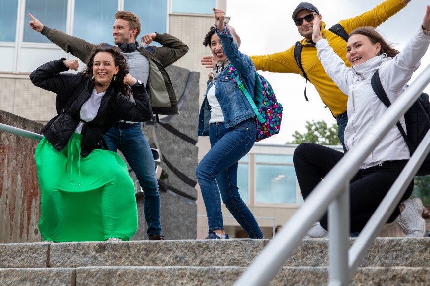 Opiskelijaryhmä poseeraa Yliopistonmäellä Tiedon portaiden yläpäässä