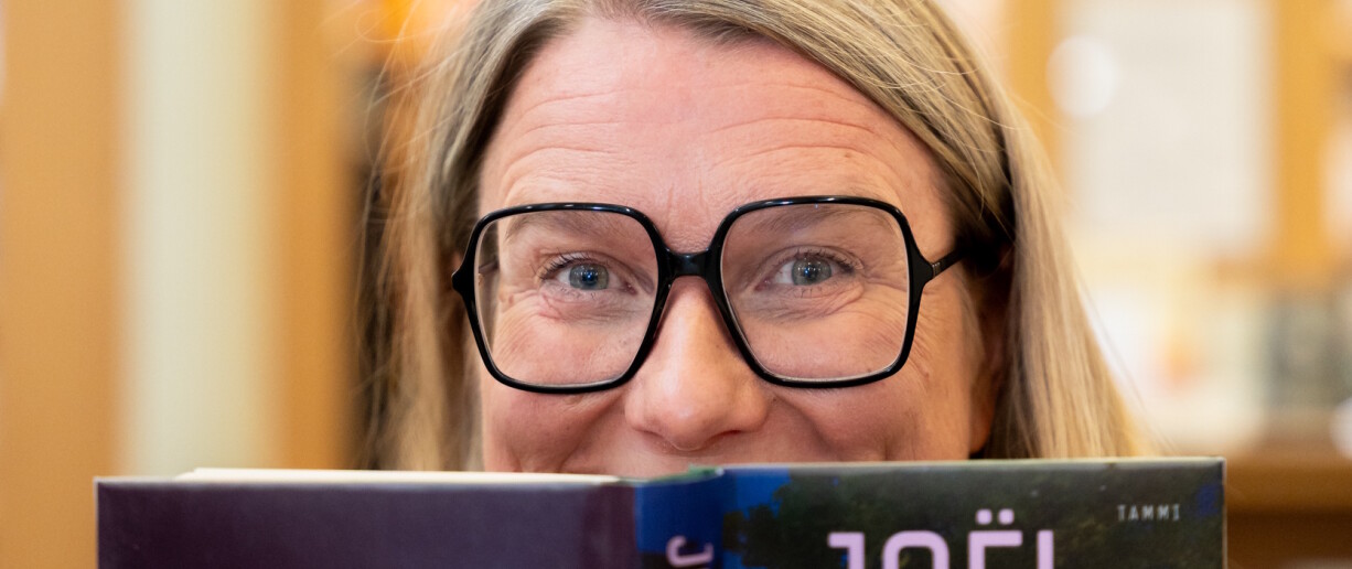 Johanna Kaakinen kurkistaa kirjan takaa.