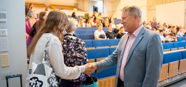 Rehtori Jukka Kola kättelee uutta opiskelijaa tervetulotilaisuudessa