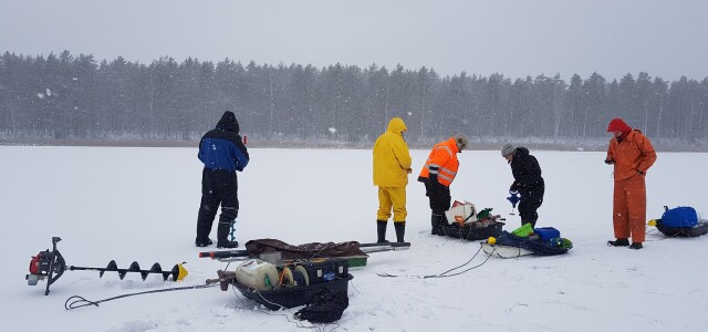 Tutkija ryhmä latvialaisjärven jäällä ottamassa näytteen järven pohjakerroksista