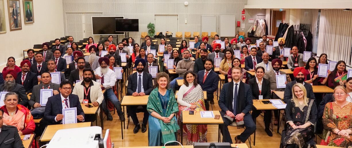 A group of people sitting in a lecture hall holding their certificates.