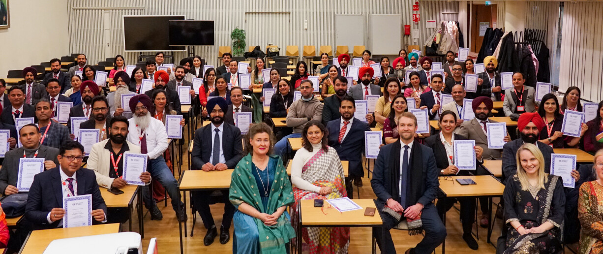 A group of people sitting in a lecture hall holding their certificates.