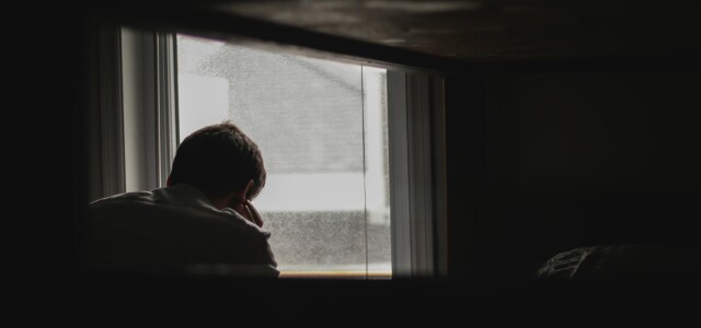Nuori henkilö istuu ikkunan äärellä.