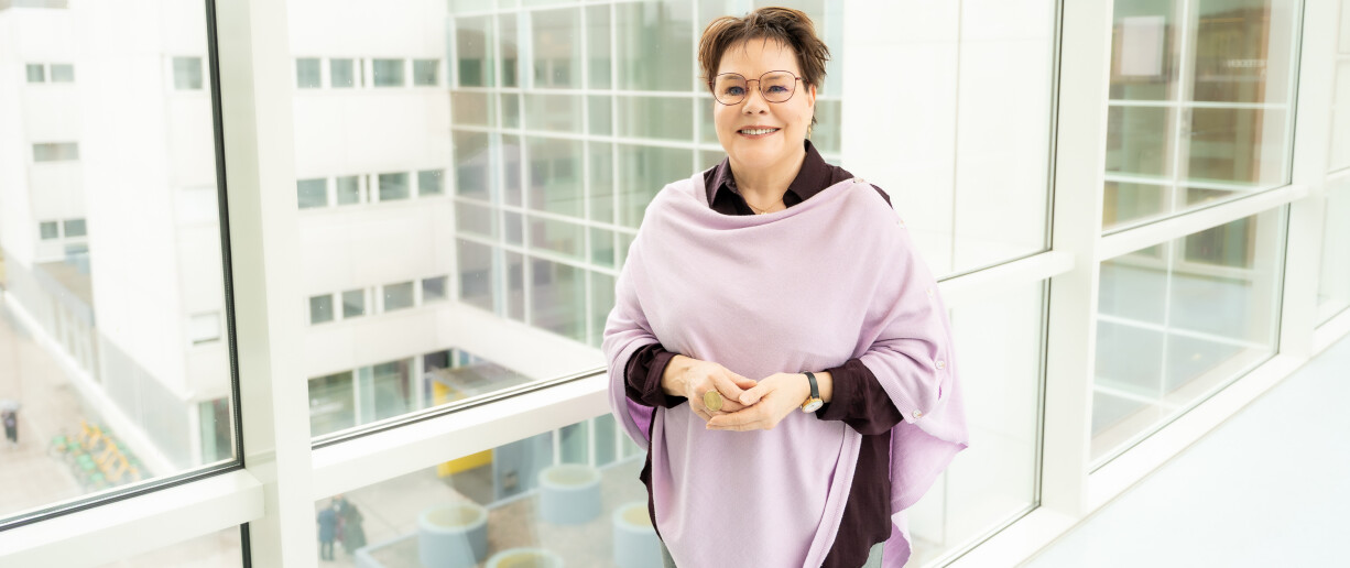 Benita Heiskanen lähikuvassa, taustalla olevasta ikkunasta näkyy Turun alakampusta.