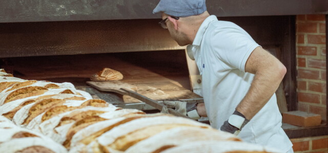 Leipuri asettelemassa leipää leipäuuniin