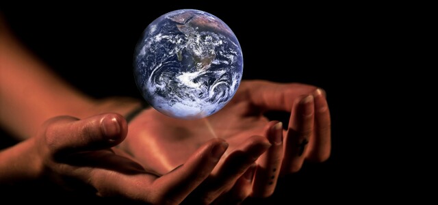 Leijuva maapallo, jonka alla ihmisen kädet kannattelevassa asennossa.