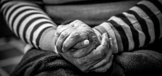 Mustavalkoinen kuva, jossa ikääntyneen henkilön kädet