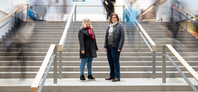 Professorit Niina Nummela ja Ulla Hytti ostoskeskuksessa, jossa taustalla vilisee ihmisiä.