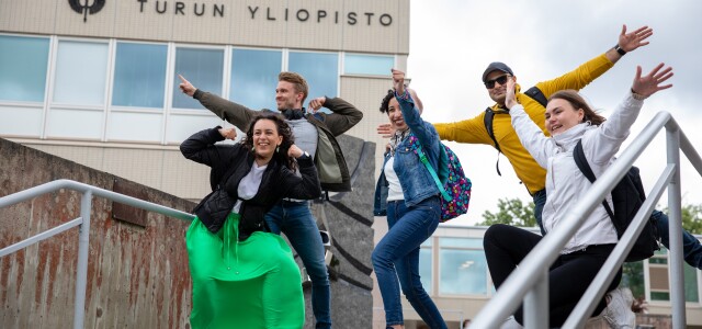 Opiskelijaryhmä poseeraa Yliopistonmäellä Tiedon portaiden yläpäässä