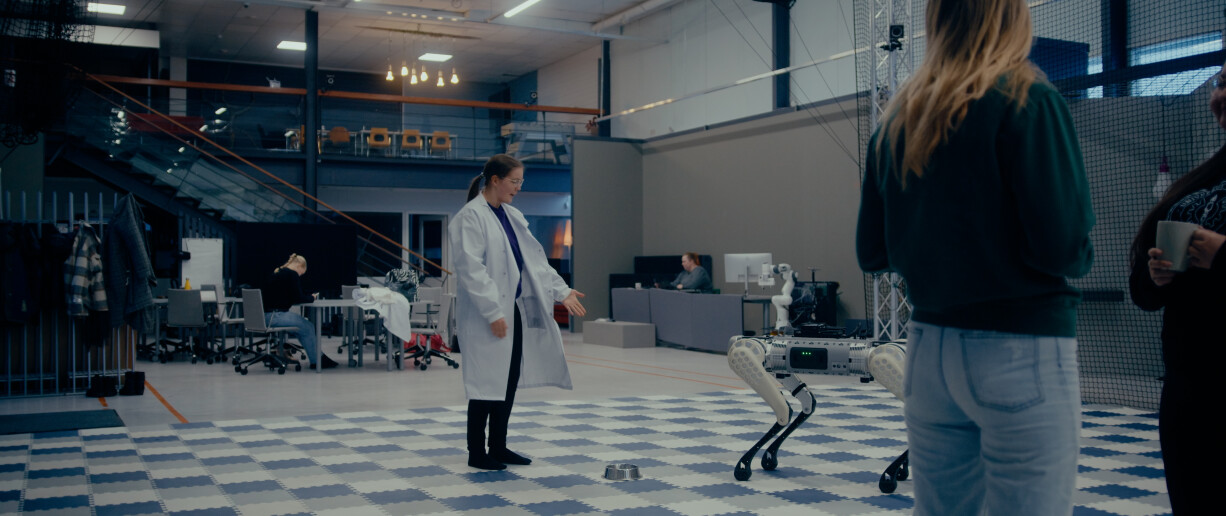 Opiskelija robottikoiran kanssa laboratoriossa.