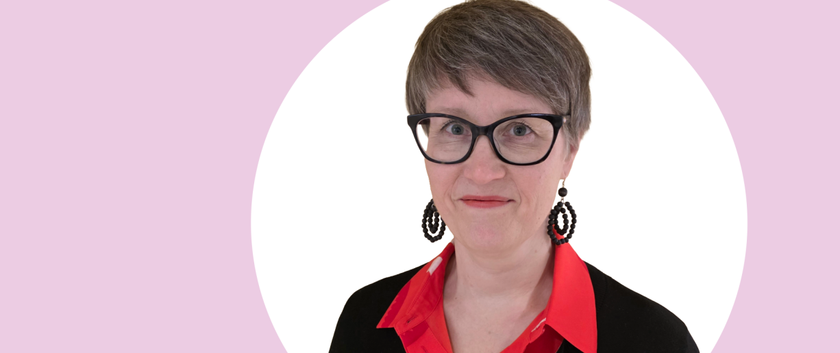 Outi Veivo lähikuvassa, tausta vaaleanpunainen ja valkoinen.