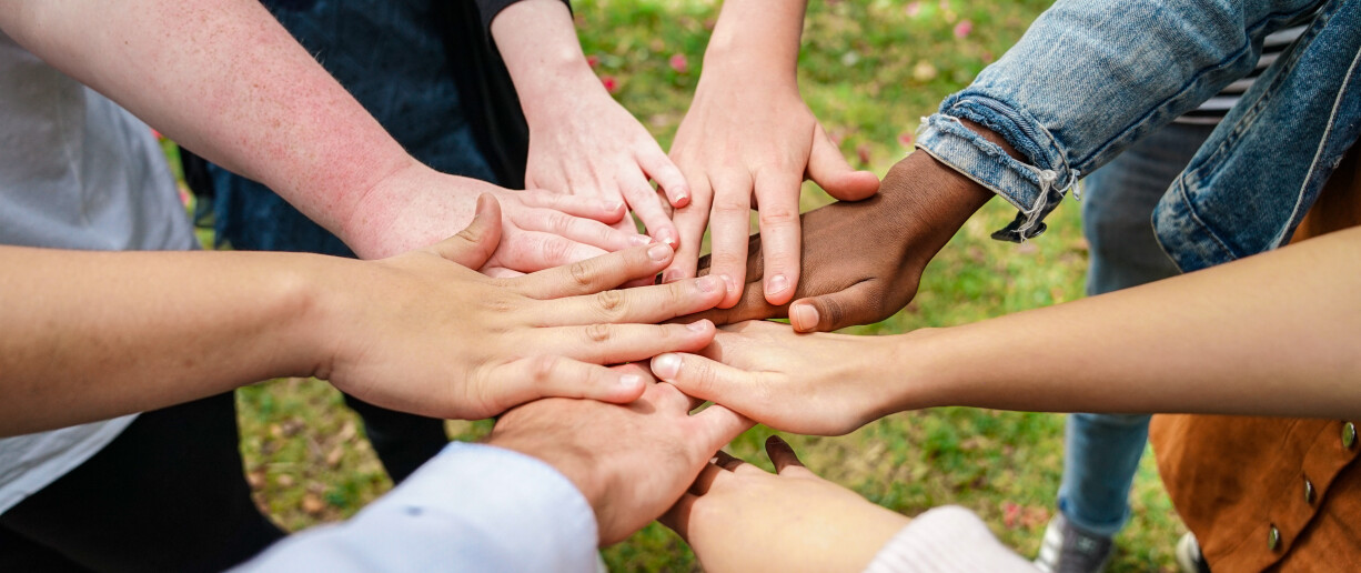Joukko ihmisiä pitää käsiä päällekkäin.