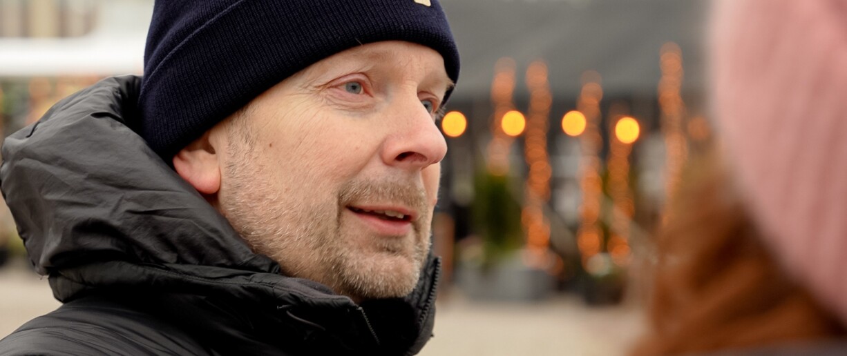 Tommi Kurki lähikuvassa kauppatorilla puhumassa henkilölle, jonka takaprofiili näkyy hieman.