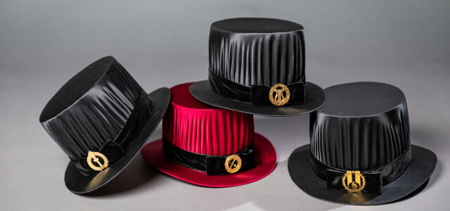 Four doctoral hats, one red, the other three black.