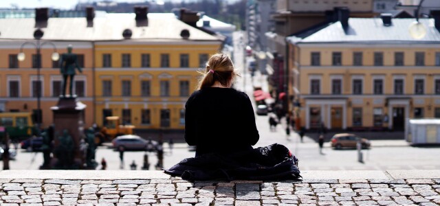 Nuori ihminen istuu Helsingin Suurkirkon portaiden yläpäässä yksin.