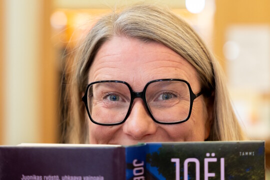 Johanna Kaakinen kurkistaa kirjan takaa.