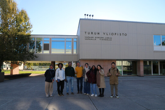 Tutkijat poseeraamassa yliopiston päärakennuksen edessä