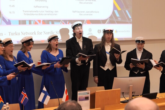 Turun yliopiston kuoro esiintymässä luentosalin edessä.