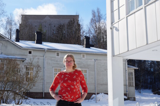 Henkilö Calonian edustalla vanha puurakennus ja vesisäiliö taustallaan aurinkoisena talvipäivänä