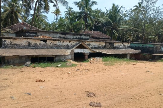 Sandy beach with derelict buildings behind showing some water damage.