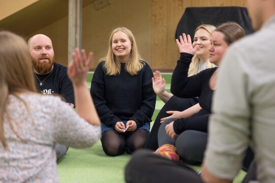 Ihmisiä istumassa lattialla keskustelemassa.