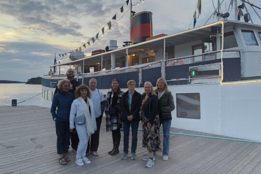 Kahdeksan ihmistä laiturilla laivan edessä.