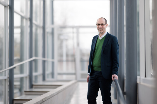 Dekaani Jaakko Järvi henkilökuvassa valoisalla lasiseinäisellä käytävällä kampuksella