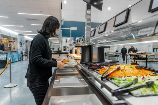 Henkilö ottamassa ruokaa lounaslinjastolla.