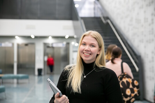 Opiskelija on menossa luennolle yliopiston aulassa läppäri mukanaan.