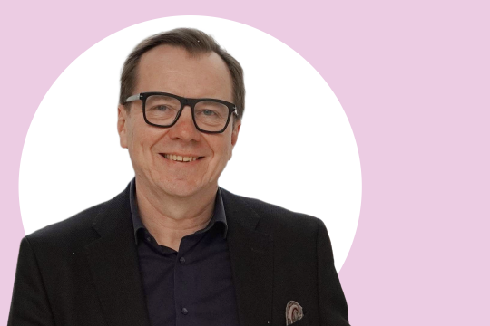 Jukka Westermarck lähikuvassa, taustalla vaaleanpunaista ja valkoista.