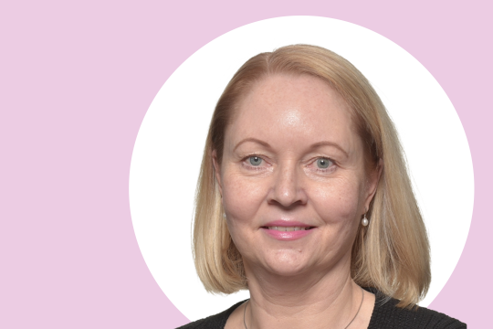 Tanja Vähämäki lähikuvassa, taustalla vaaleanpunaista ja valkoista.