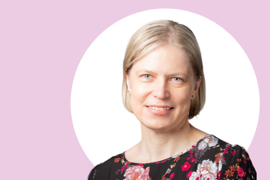 Minna Stolt lähikuvassa, taustalla vaaleanpunaista ja valkoista.