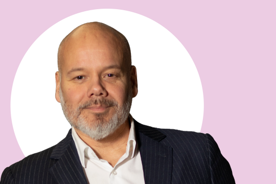 Heikki Jaatinen lähikuvassa, taustalla vaaleanpunaista ja valkoista.