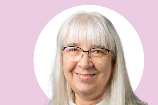 Katriina Siivonen lähikuvassa, taustalla valkoista ja vaaleanpunaista.