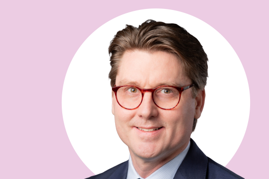 Tuomas Kiviniemi lähikuvassa, taustalla vaaleanpunaista ja valkoista.