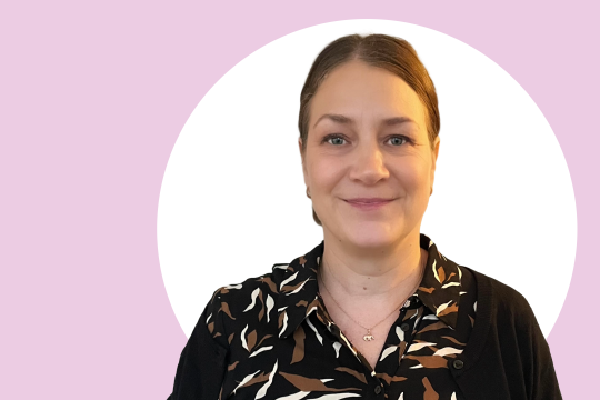 Tiina Kurvinen lähikuvassa, taustalla vaaleanpunaista ja valkoista.