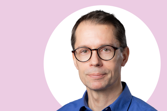 Pekka Laukkanen lähikuvassa, taustalla valkoista ja vaaleanpunaista.